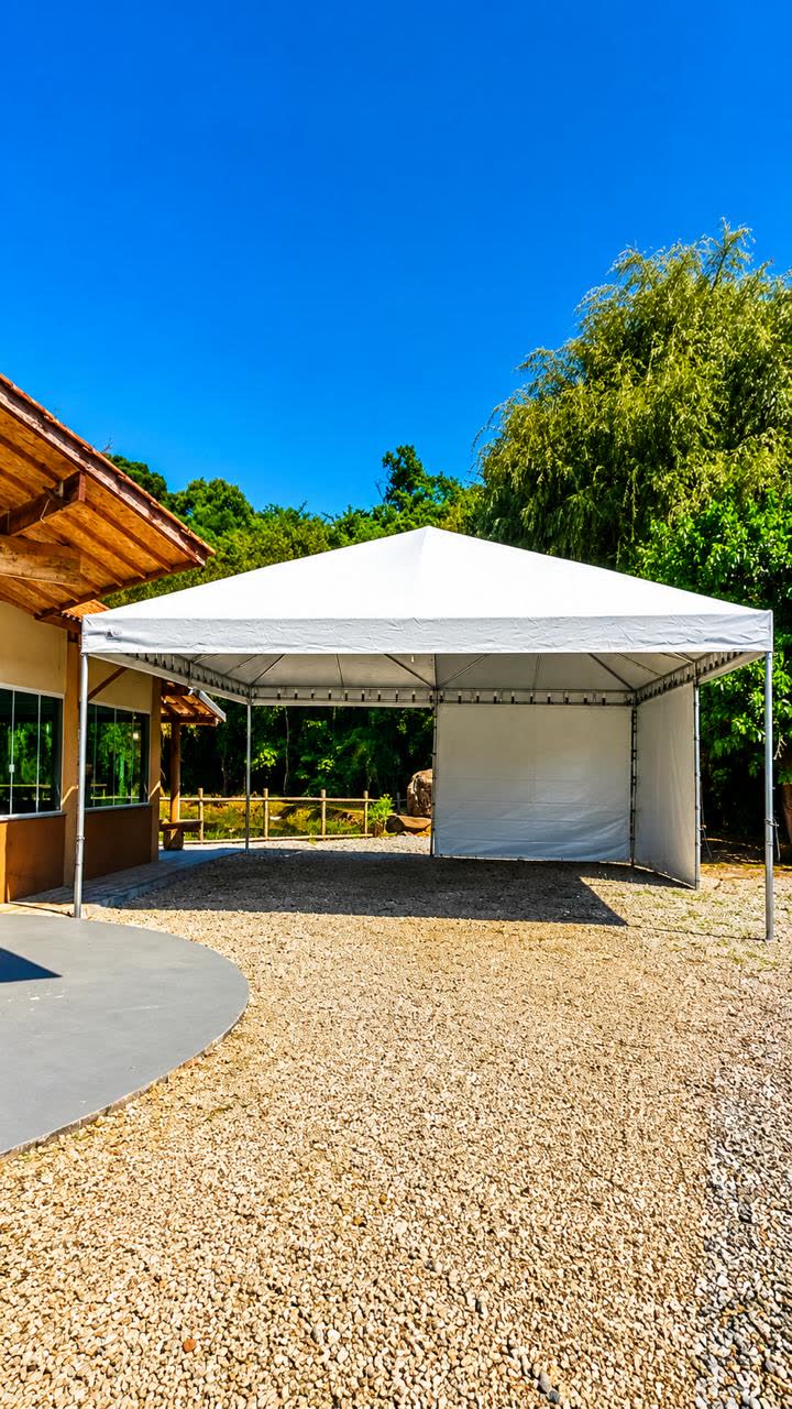 Tenda branca grande com fechamento lateral ao lado de uma casa