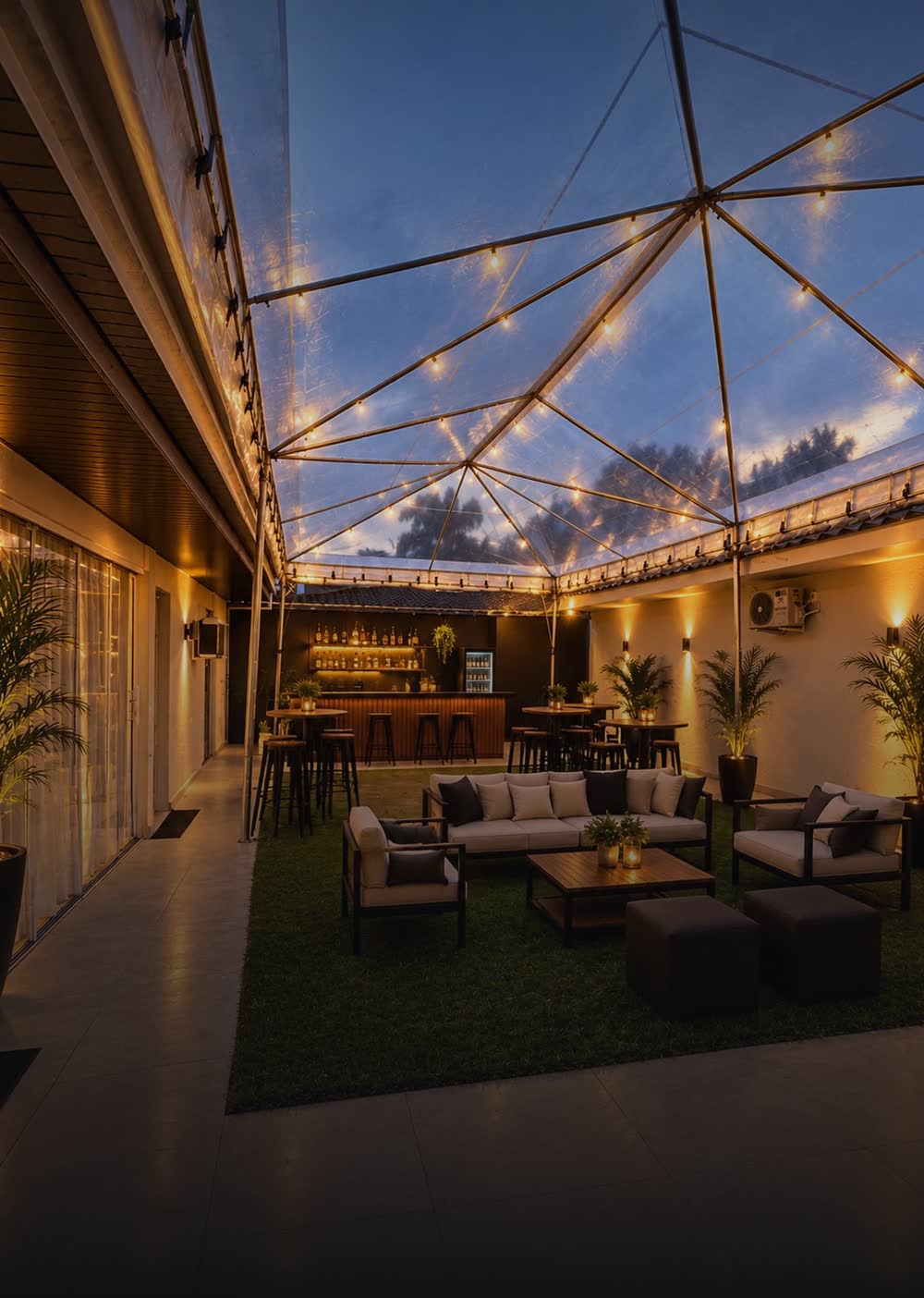 Lounge com sofás sob tenda cristal iluminada à noite